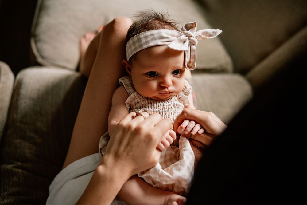A set of five intimate black and white photographs showing a baby playing and expressing different emotions.