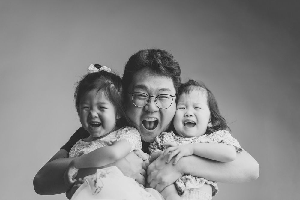 Black and white portrait of joyful laughter between a parent and two small children.