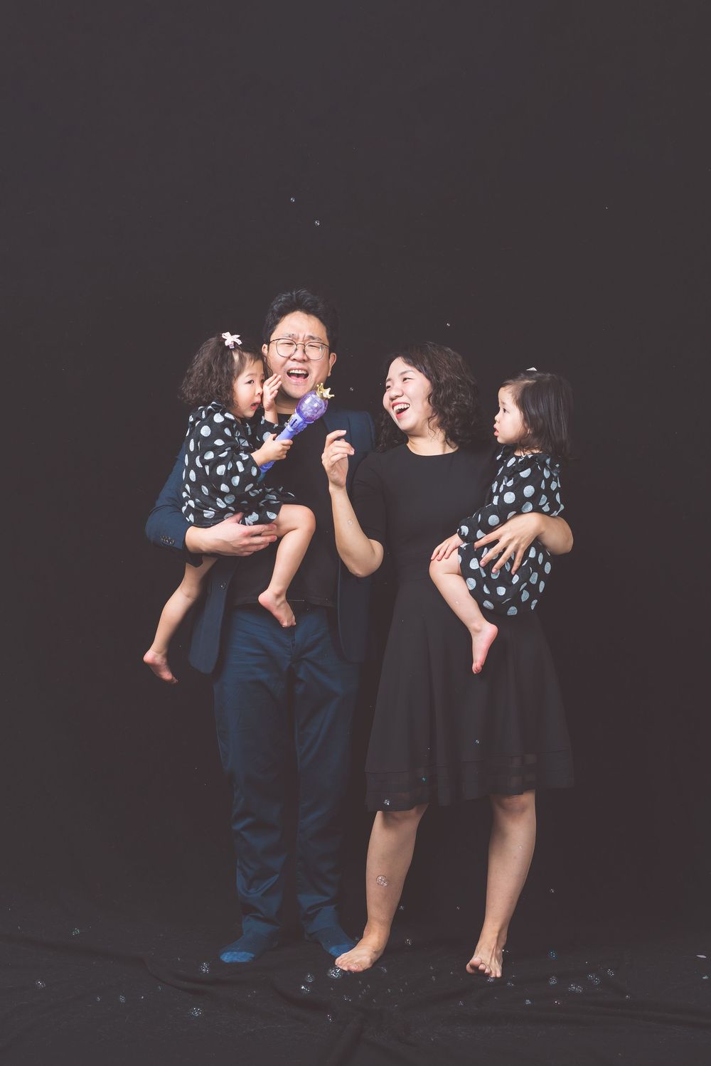 A candid family portrait with matching polka dot dresses against dark background.
