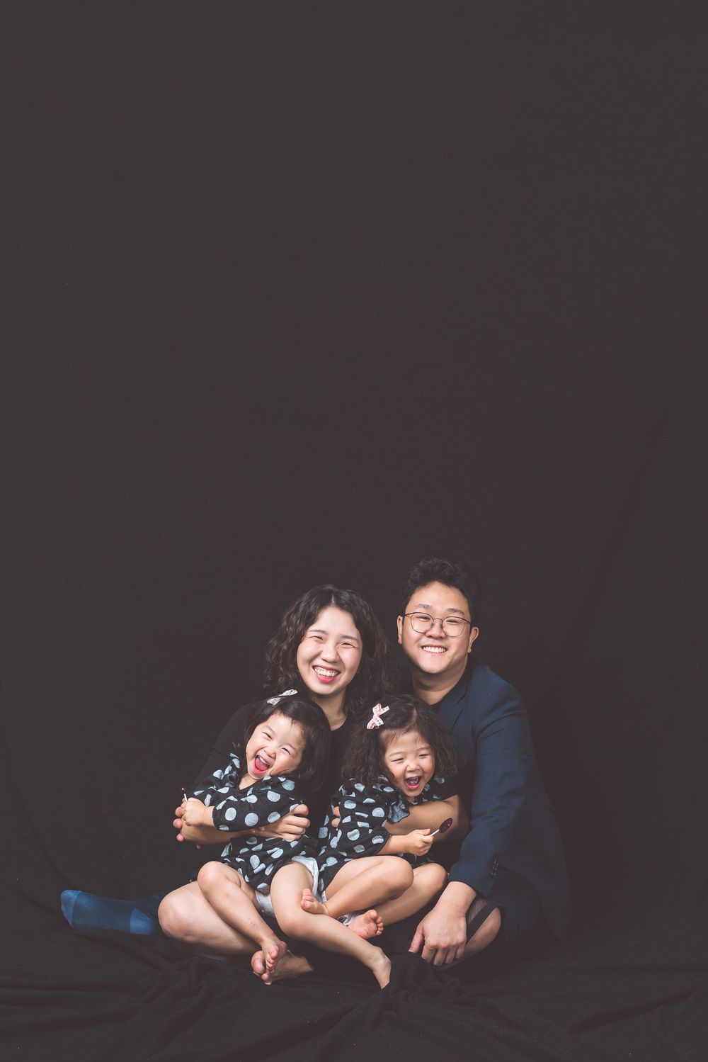 A family portrait with matching outfits against a dark background.