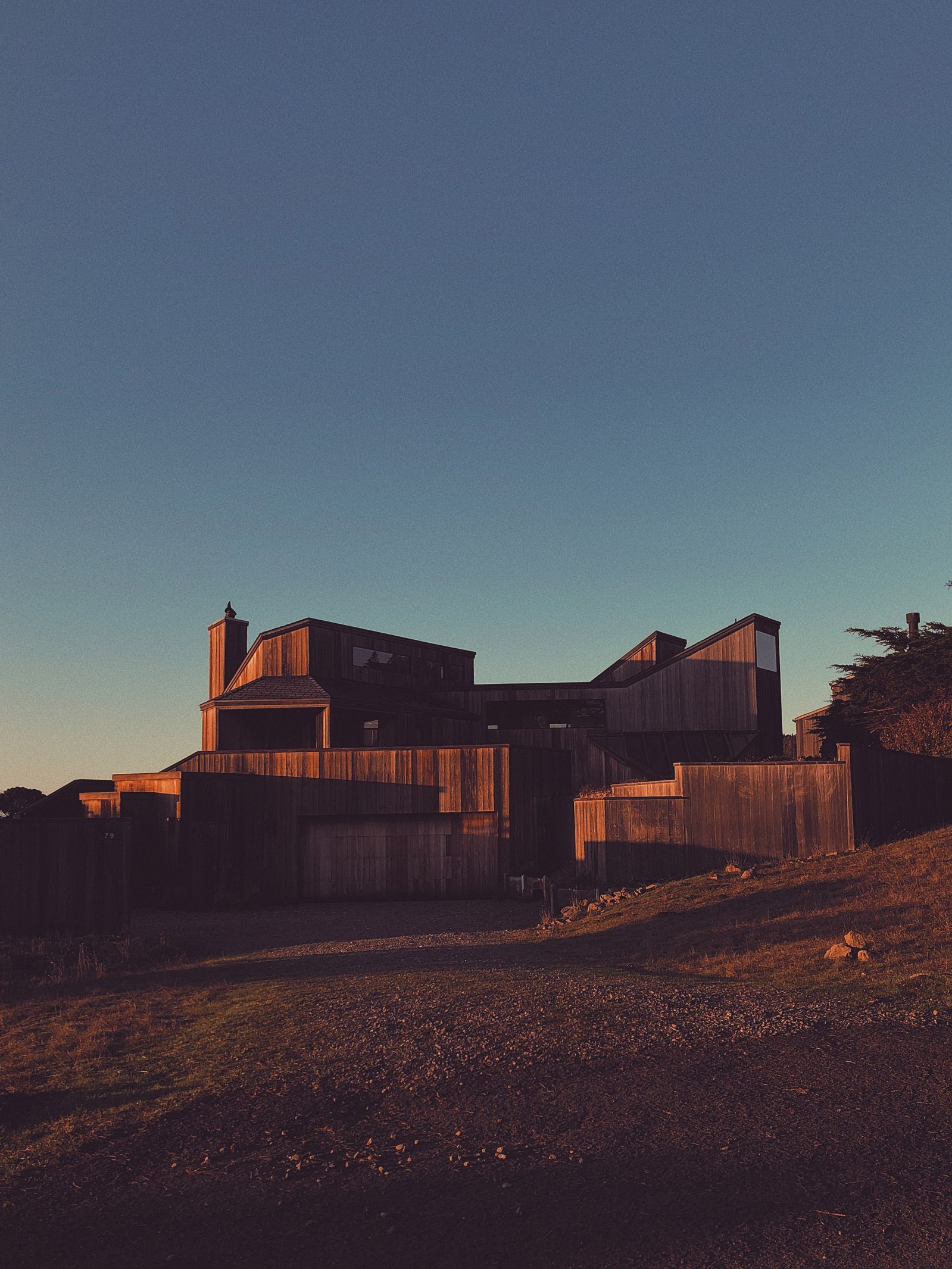 Modern hillside home captured at sunset with dramatic angular architecture.