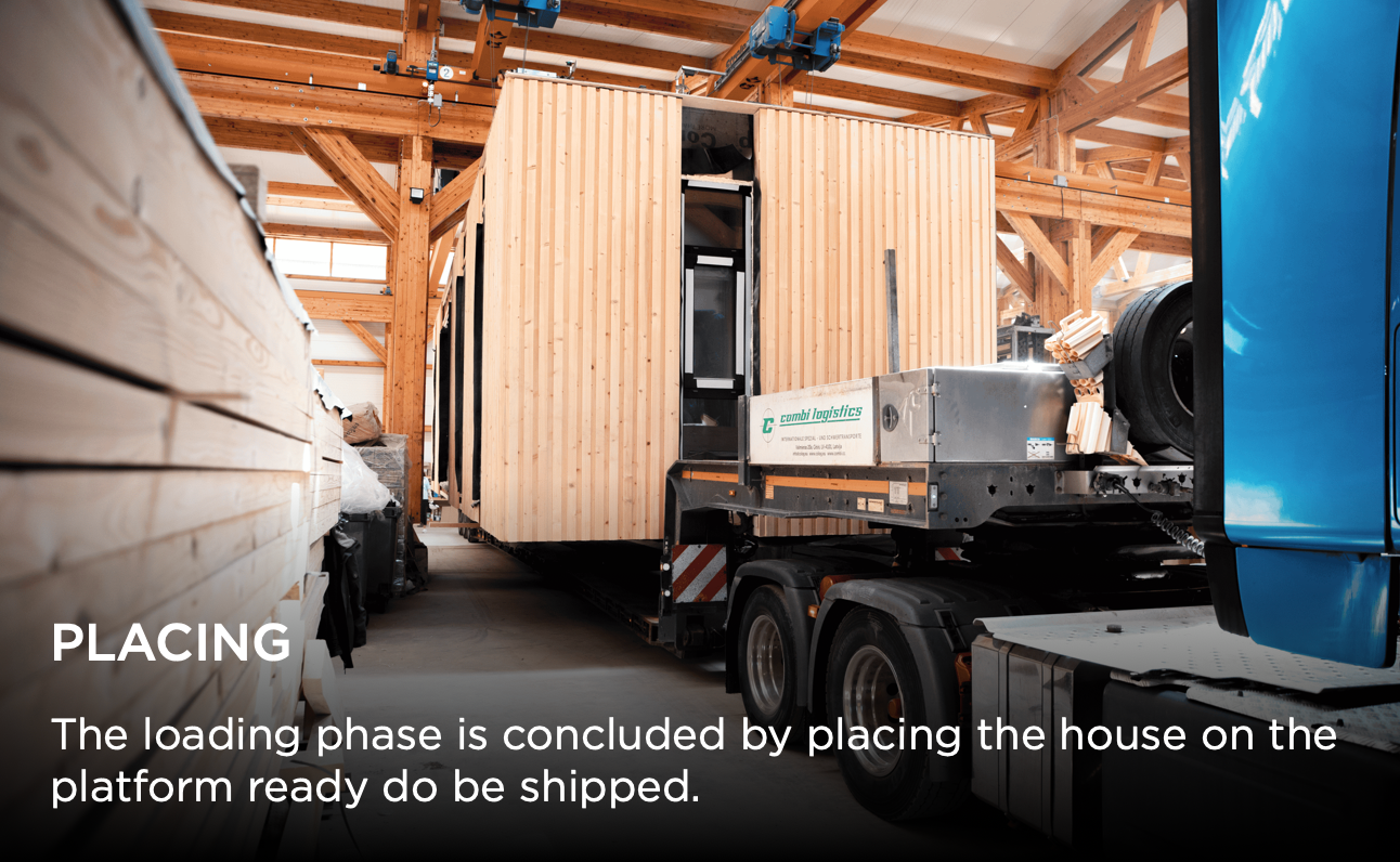 Construction crew lifts modular house section using crane beams and forklifts during prefab home assembly process.