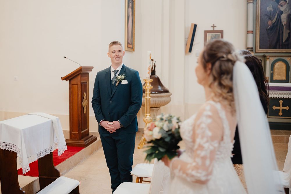 A joyful moment captured during a wedding ceremony in a church with delicate decor and white altar linens.