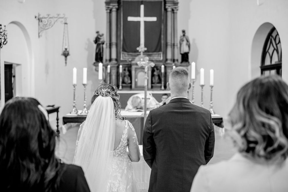 A couple stands at the altar of a church during their wedding ceremony as candles illuminate the sanctuary.