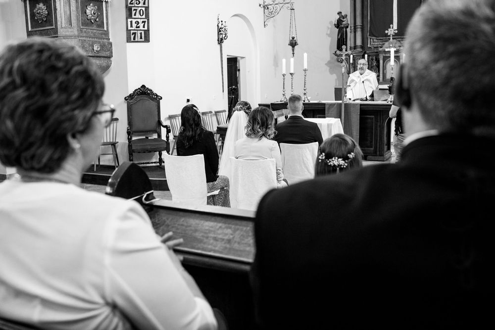 Black and white photo showing a Catholic mass ceremony taking place inside a traditional church setting.