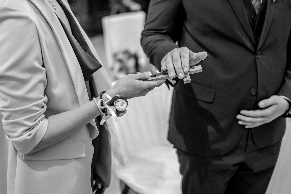 Black and white closeup of exchanging rings during an outdoor wedding ceremony.