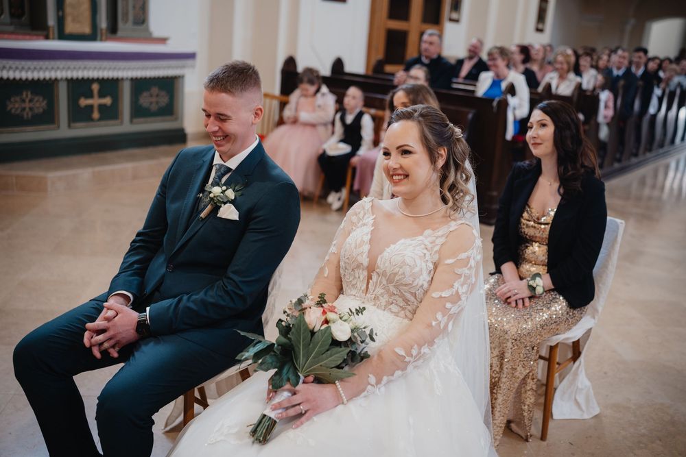 A traditional wedding ceremony scene inside a church with a couple seated in front during their marriage celebration.