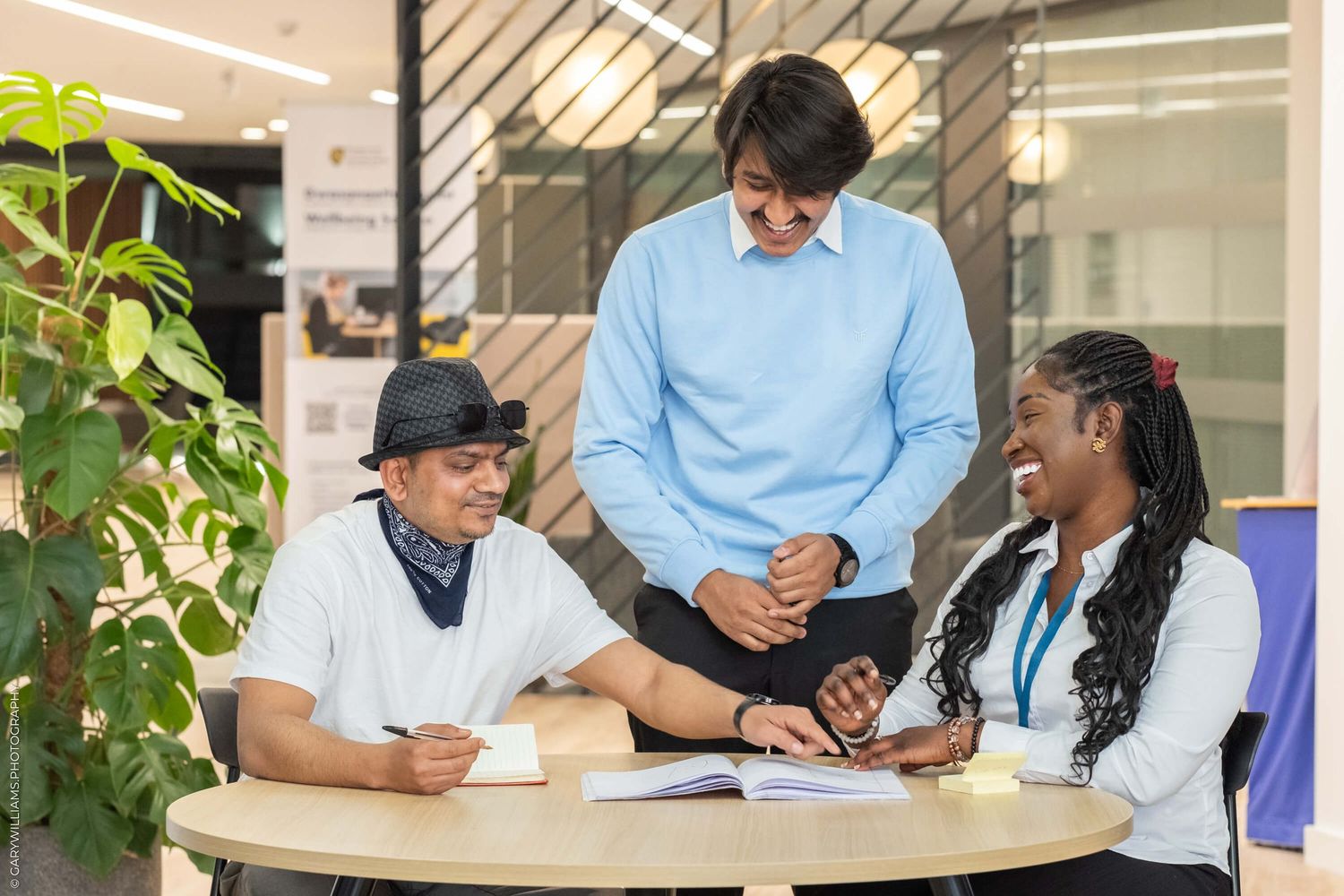 Small group discussing documents and collaborating at a modern office workspace with indoor plants.