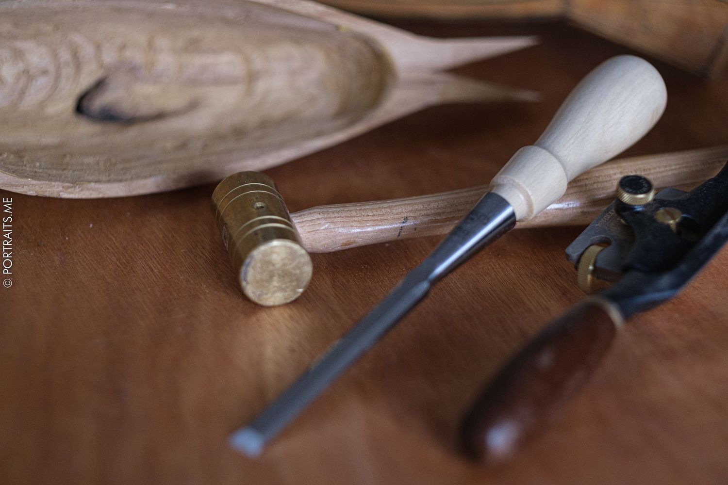 Vintage woodworking tools including chisel and mallet on leather surface.