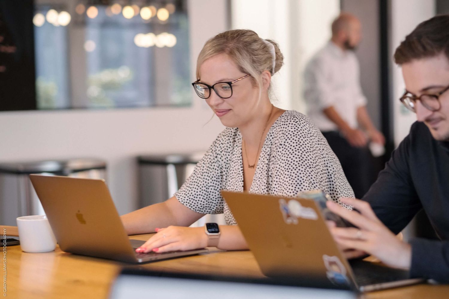 People working on laptops in modern office meeting room.