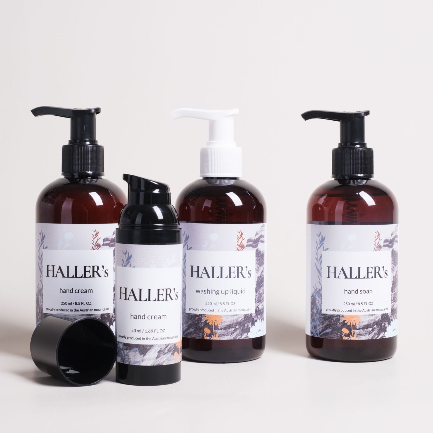 Collection of dark amber glass bottles with Haller's branded pump dispensers against white background.