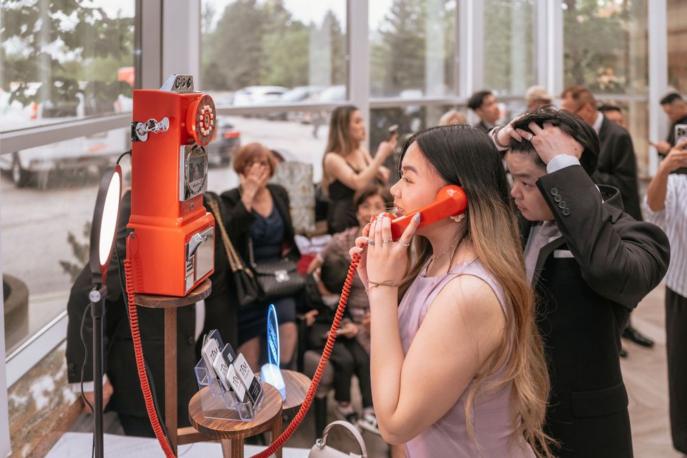 People look through viewfinders at an outdoor observation deck while sightseeing on a cloudy day.