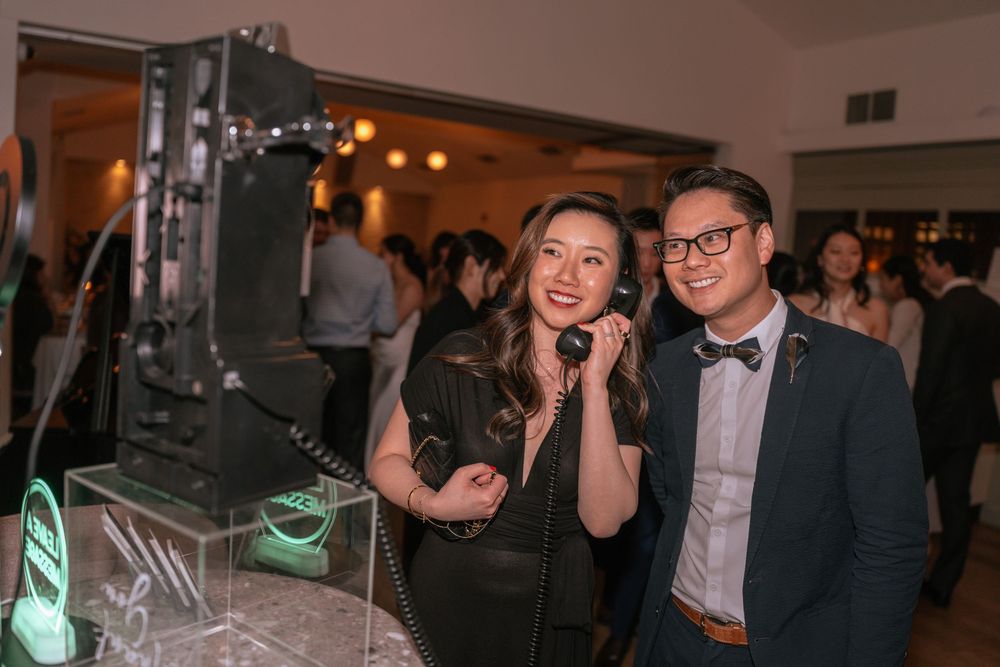 Party guests pose next to a professional DJ setup with glowing green lighting at an evening event.
