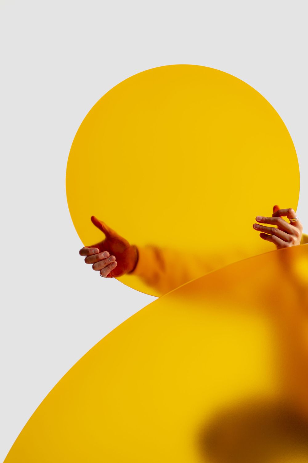 Outstretched hands gesturing against a vibrant yellow circular background.