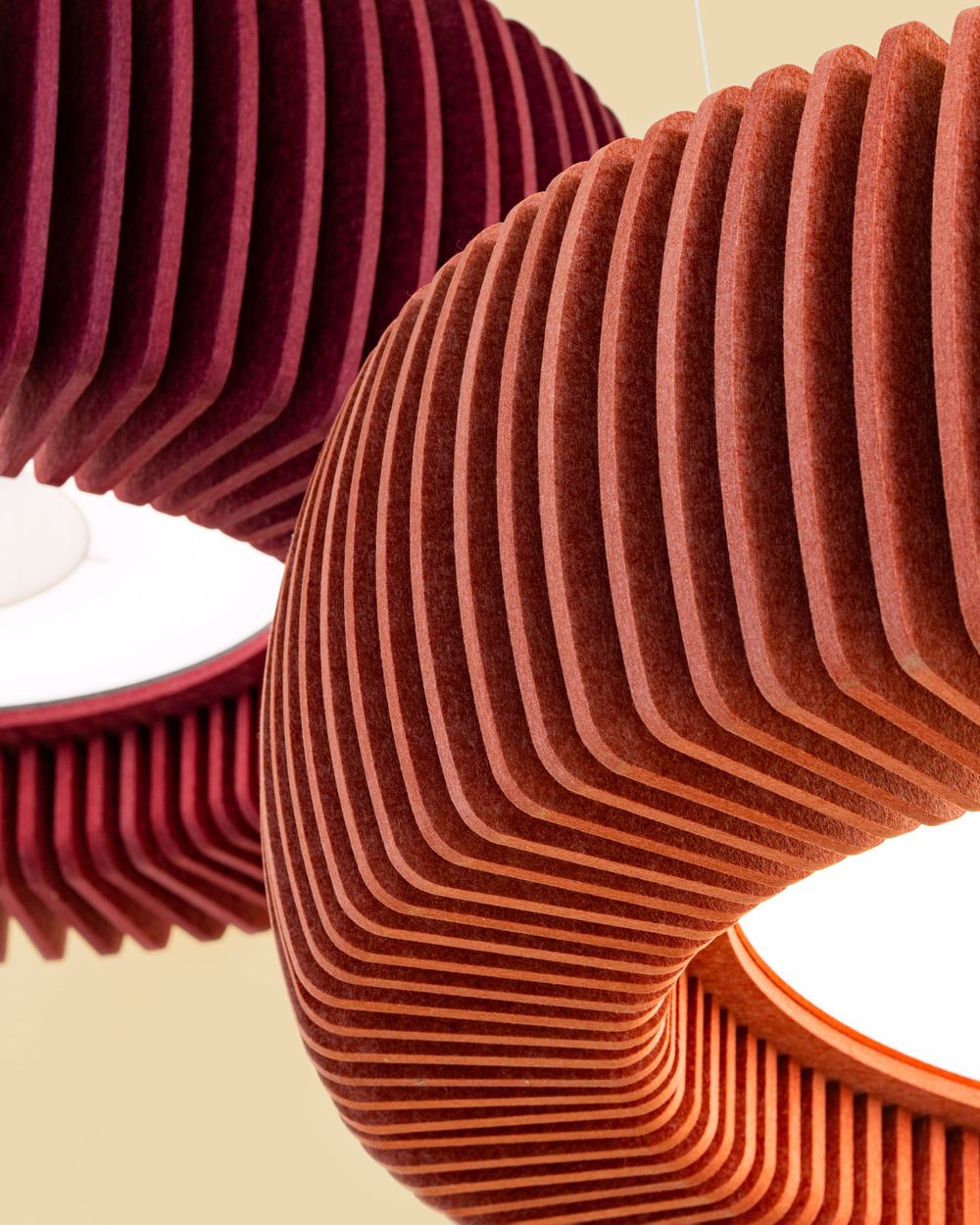 Modern pendant lamps with ribbed wave patterns in burgundy and copper colors create dramatic sculptural lighting.
