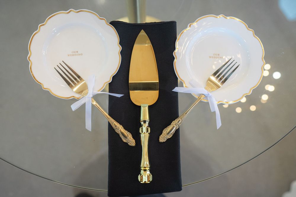 Wedding place setting with gold-rimmed plates and utensils arranged on dark fabric.