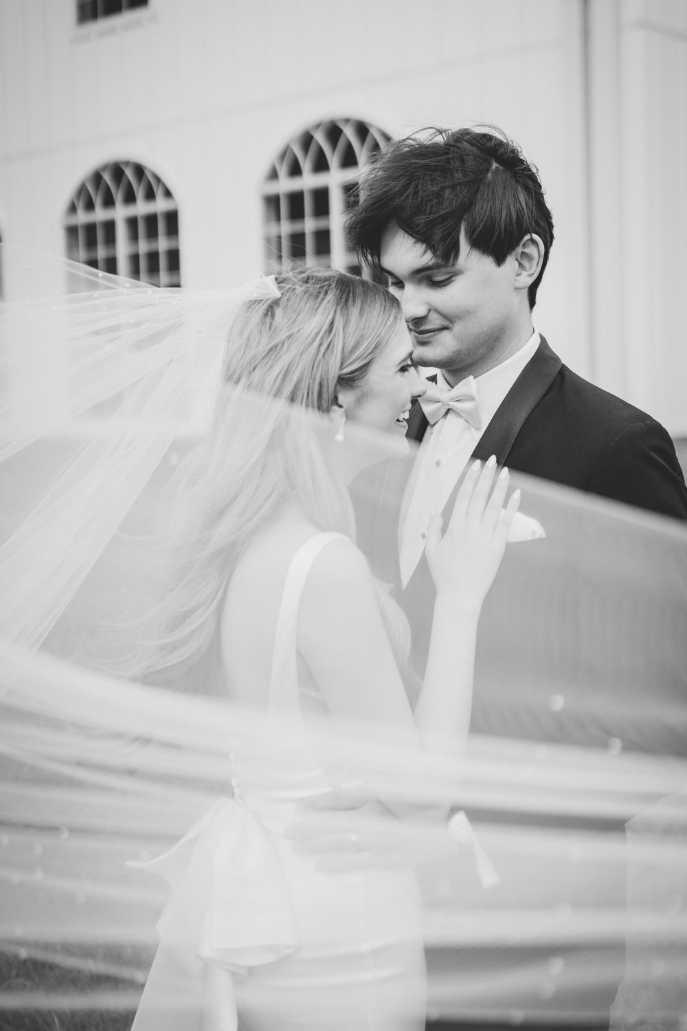 Romantic black and white portrait of newlyweds with flowing veil.