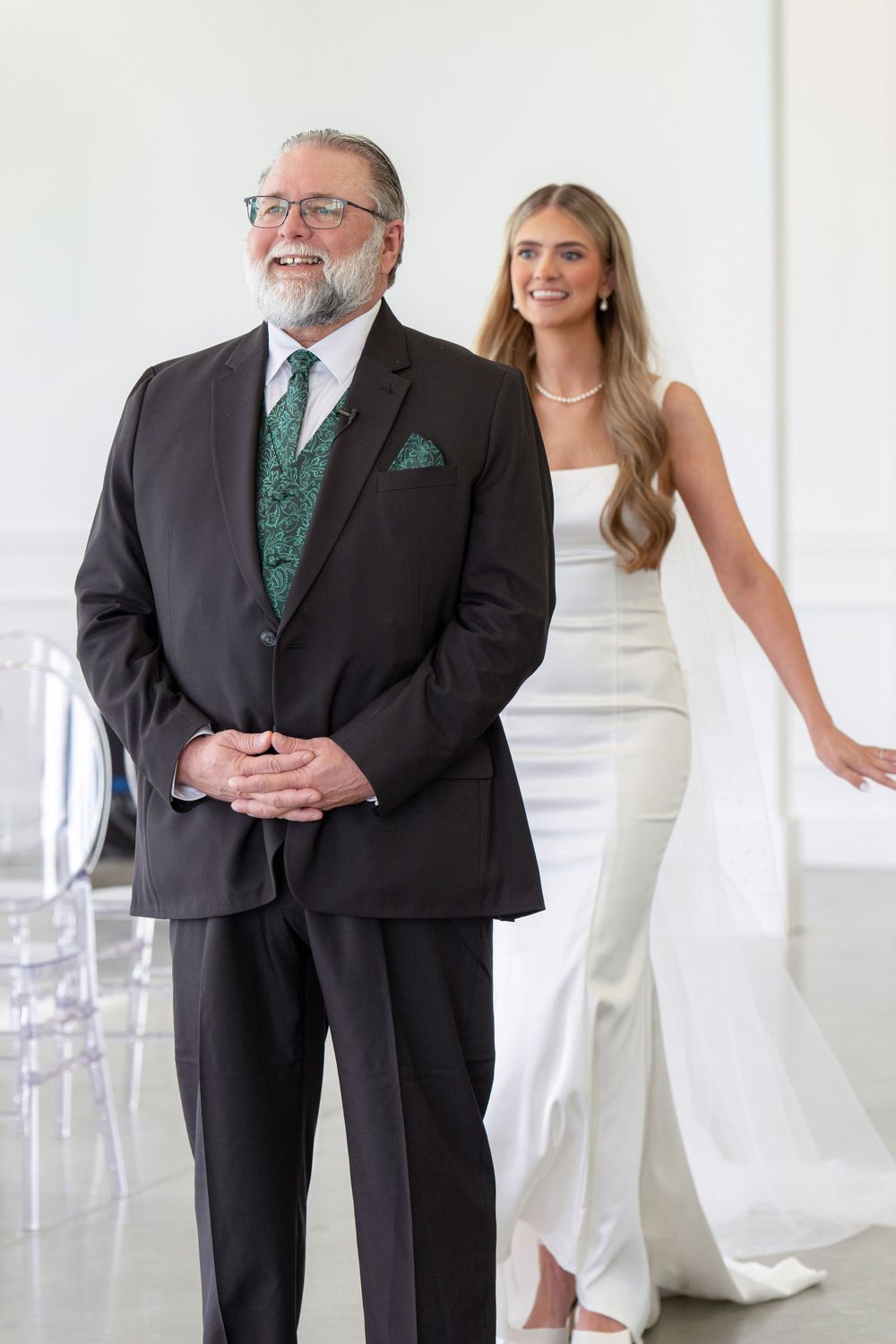Emotional father-daughter moment captured in modern white venue space.