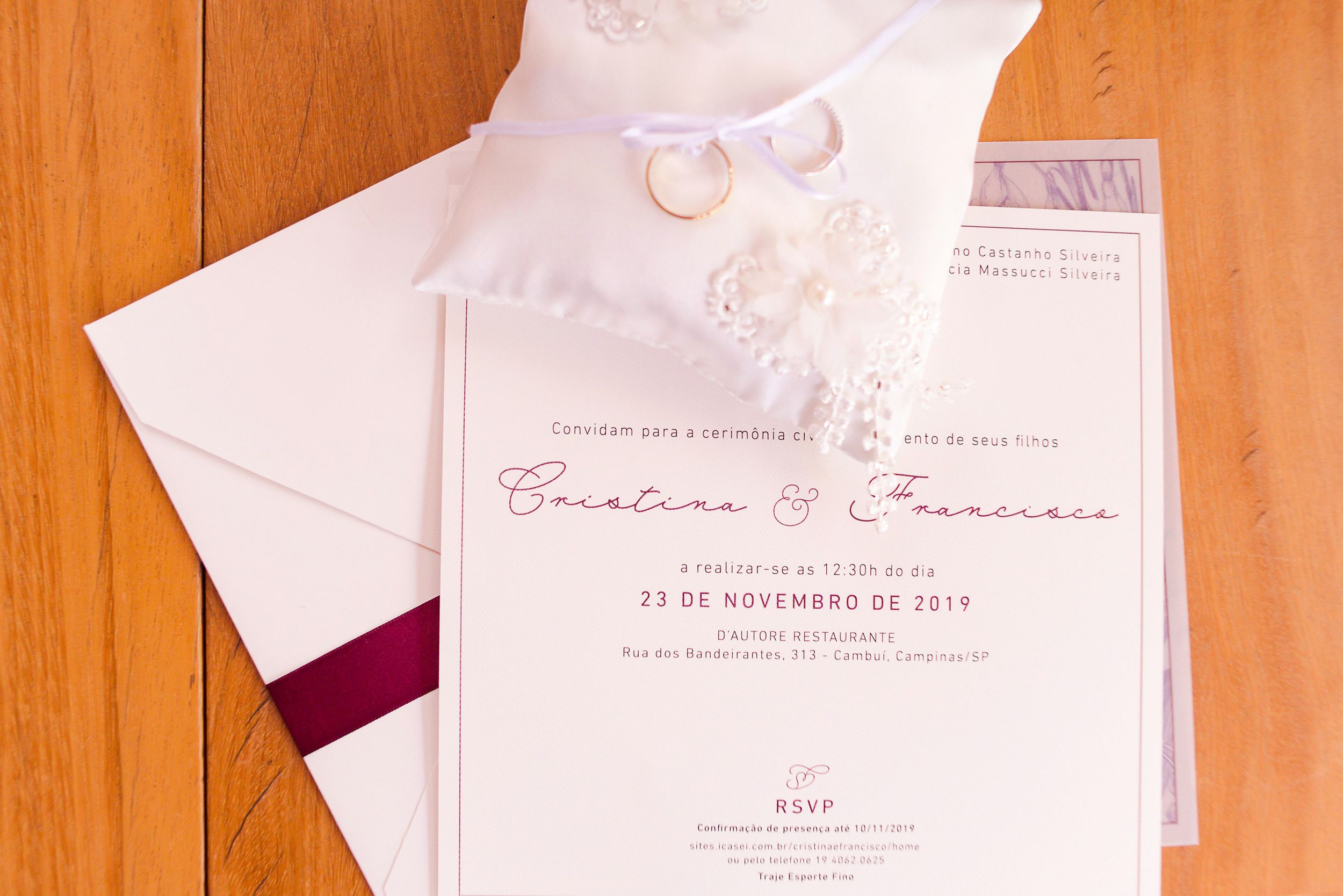 Elegant white and burgundy wedding invitation with lace details and envelope on a wooden surface.