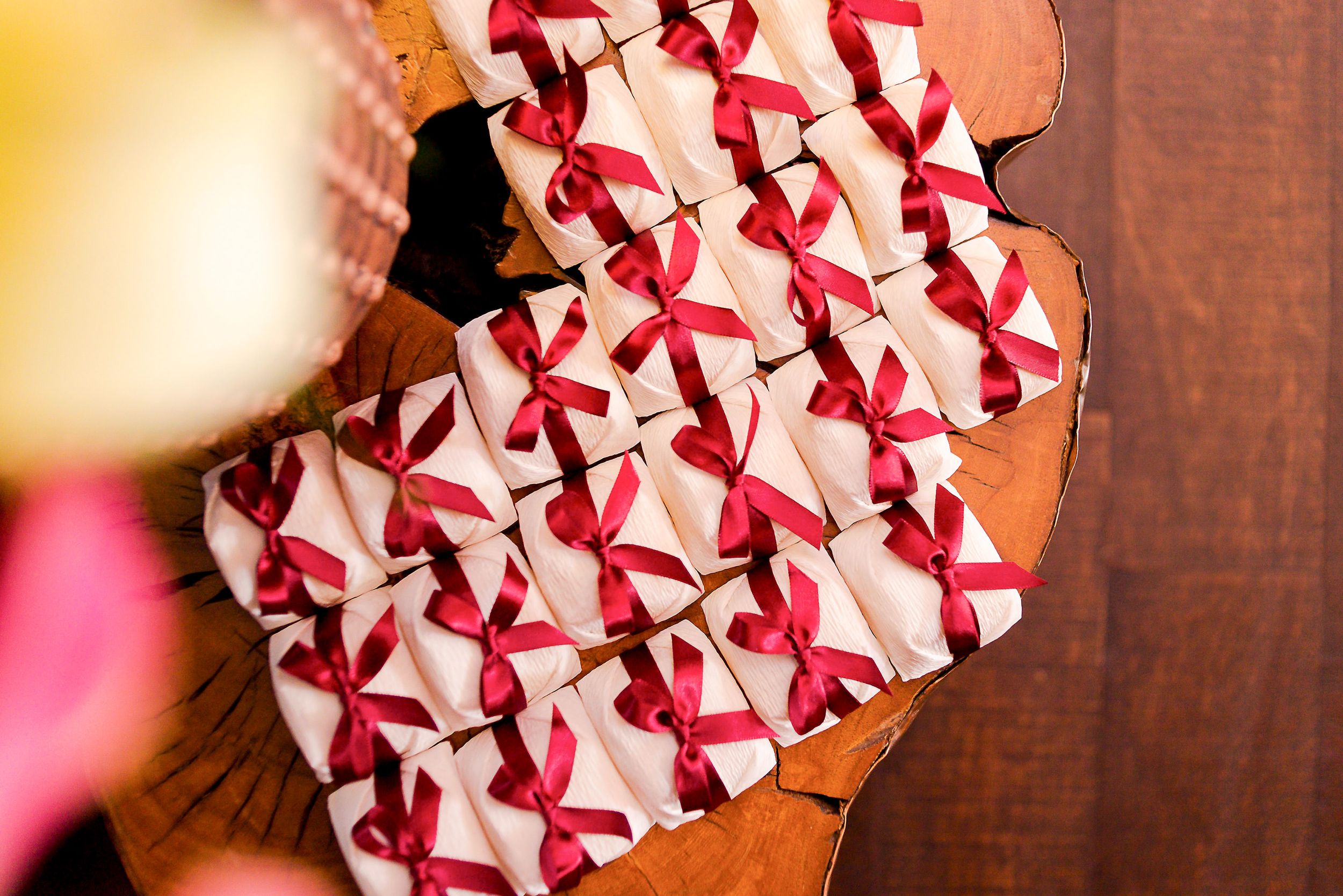 A pink and white heart-shaped gift box with red ribbon pattern sitting on a wooden surface.