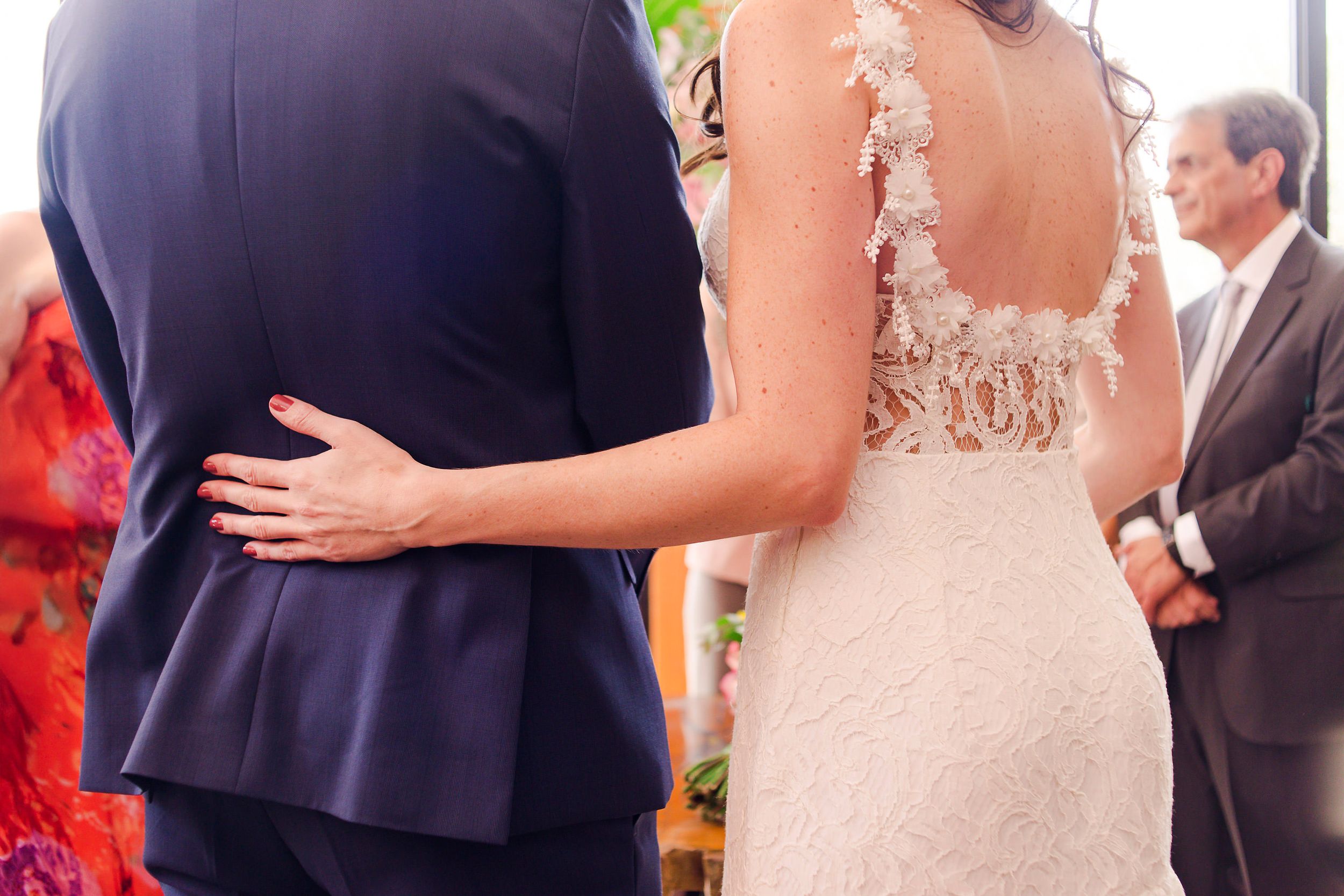 Close-up view of a couple embracing at a wedding, with the bride wearing a delicate lace back dress.
