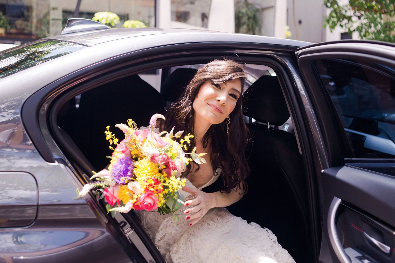 A colorful bouquet of spring flowers is held inside a black car.