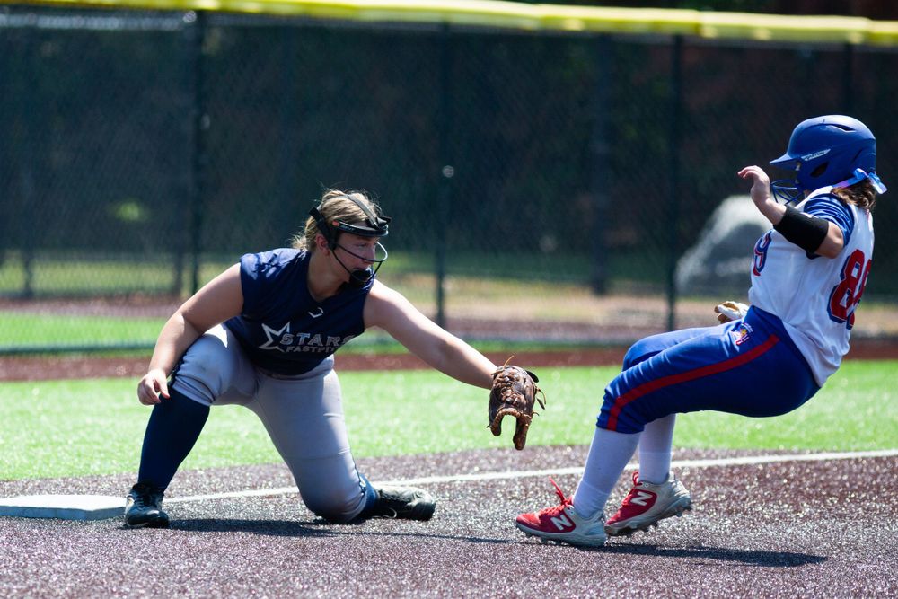A baseball infielder attempts to tag out a sliding baserunner during a competitive game on a sunny day.