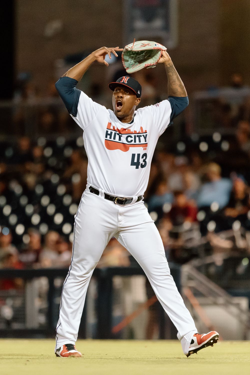 Baseball player in white Hi City uniform number 43 celebrates with animated gesture during game on field.