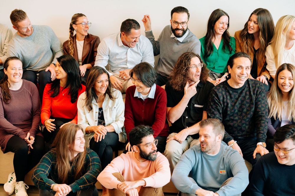 Large diverse group seated together in casual office environment.
