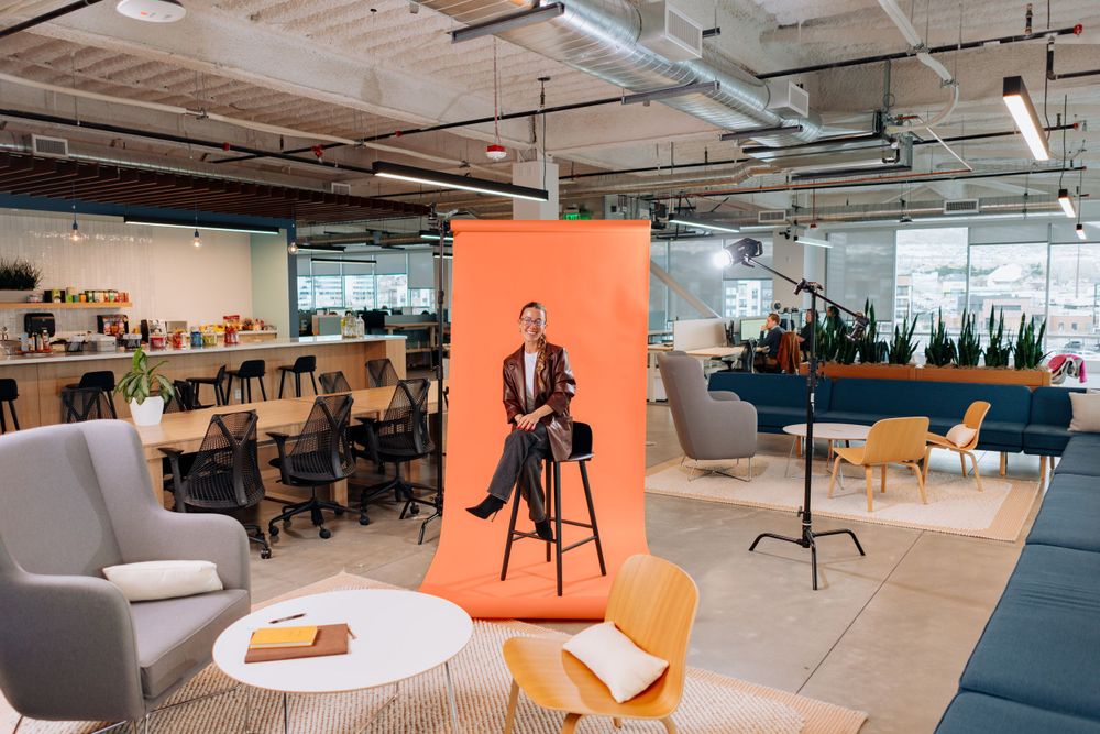 Open office interior with orange backdrop and modern furniture setup.