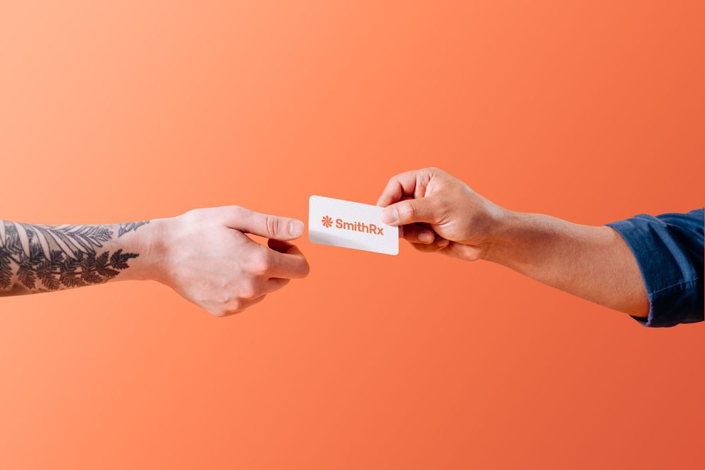 Two hands exchanging a white business card against a coral orange background.