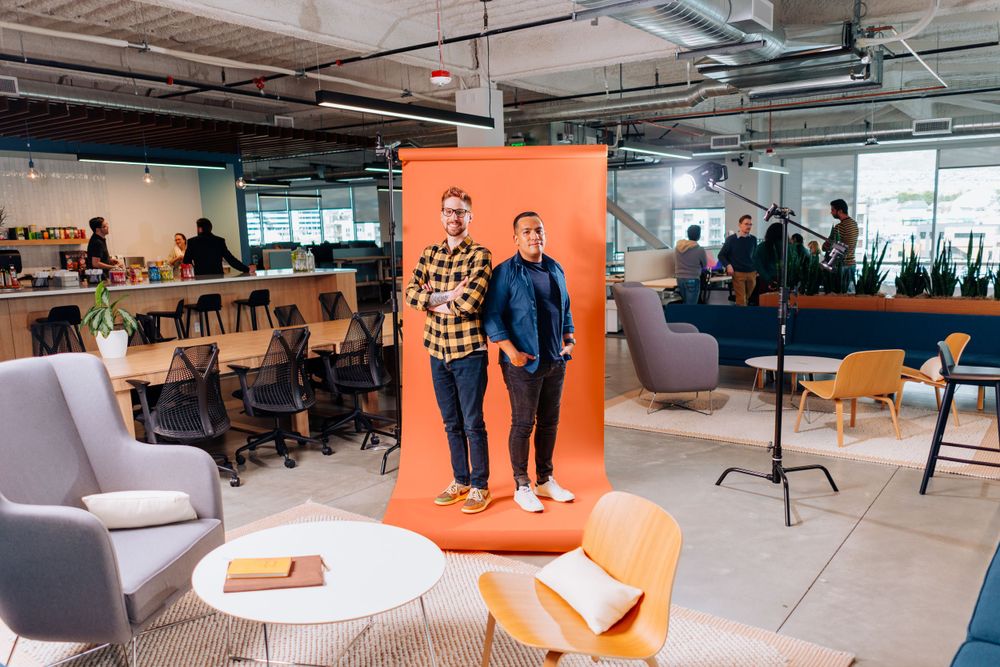 Modern office space with orange backdrop and grey chairs in an open workspace environment.