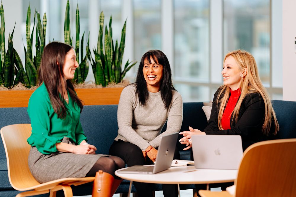 Three professionals having a meeting in a bright office space with plants.