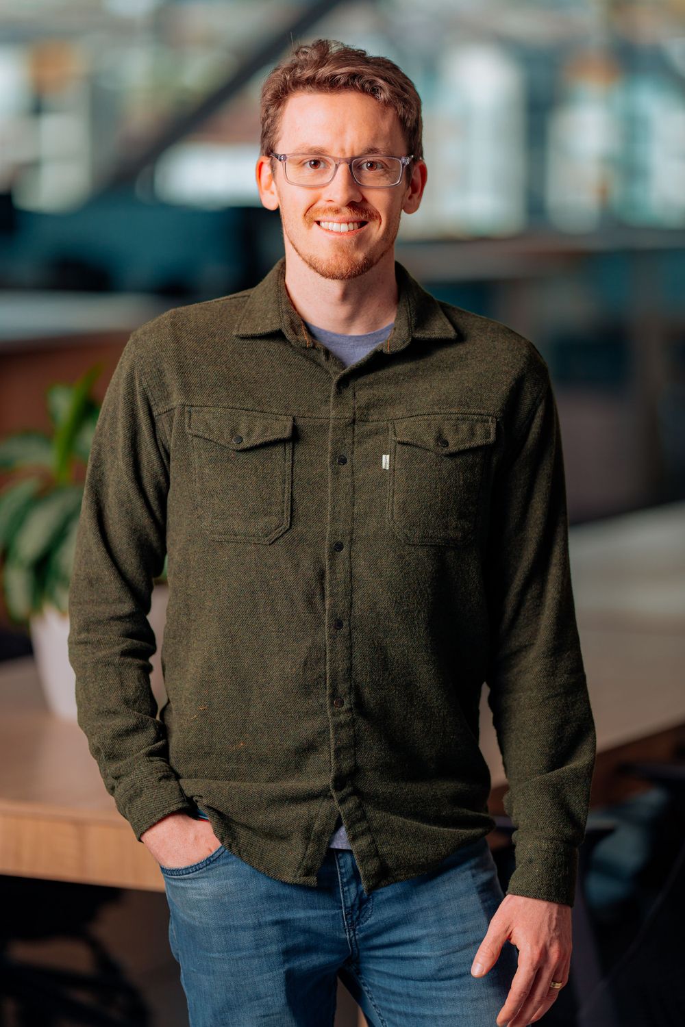 Professional in casual green button-up shirt standing in modern office setting.