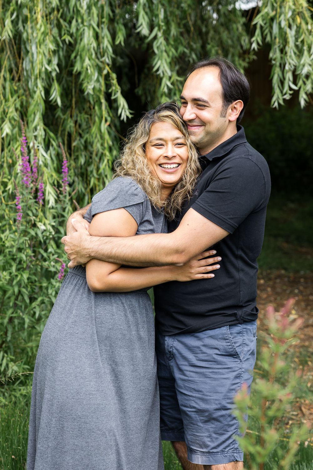 husband and wife hugging under a tree