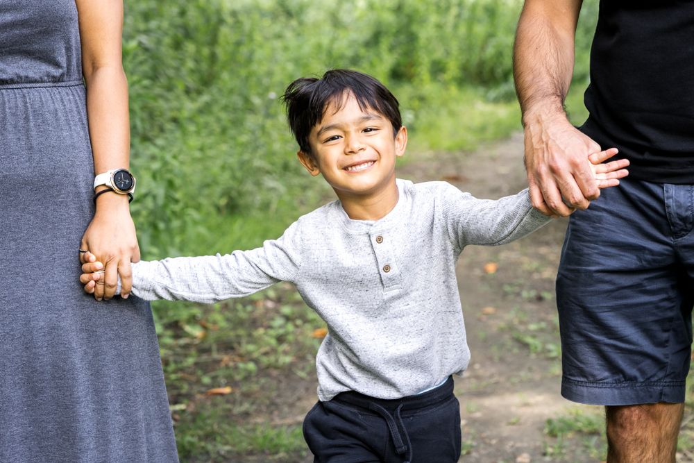 little boy holding hands with his parents