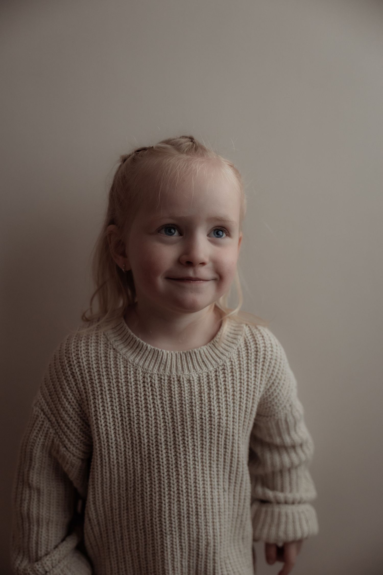 Portret van een vrolijk meisje van twee met blozende wangen en een scheve glimlach.