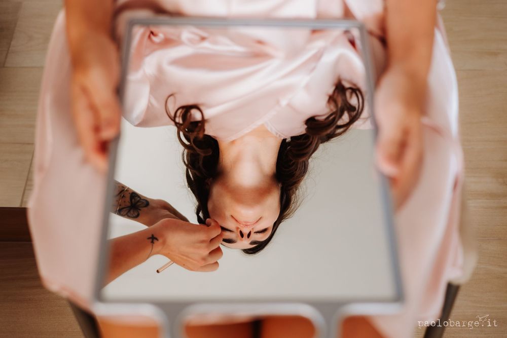 Overhead view of someone wearing a pink dress looking down at a reflective surface.