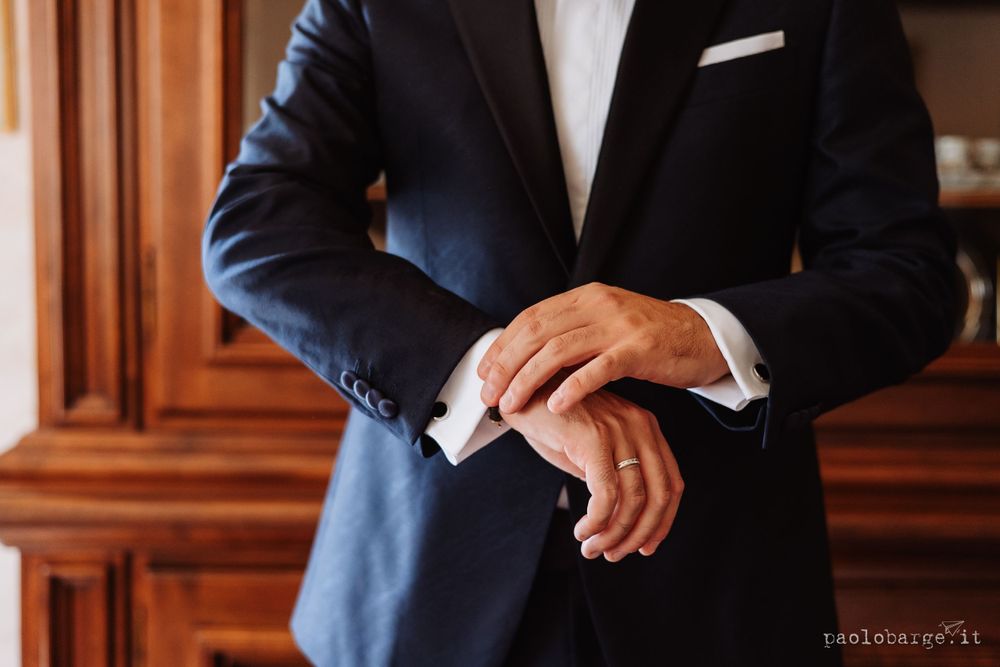Close-up of person in navy suit adjusting their watch or sleeve.