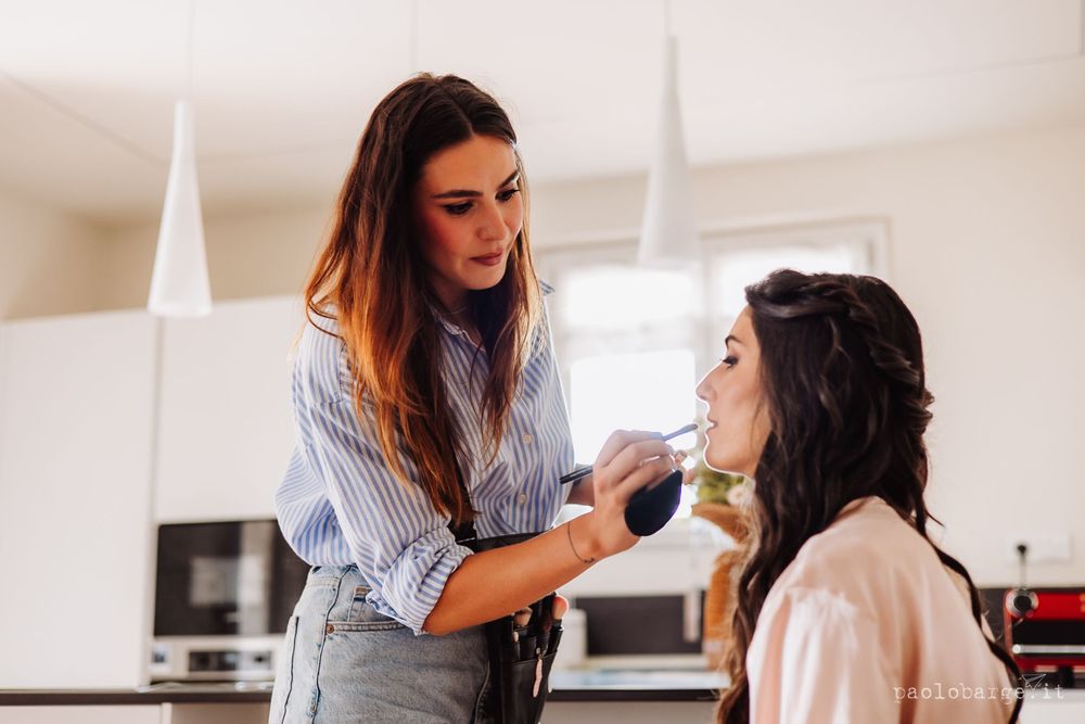 Professional makeup application scene in bright modern kitchen.