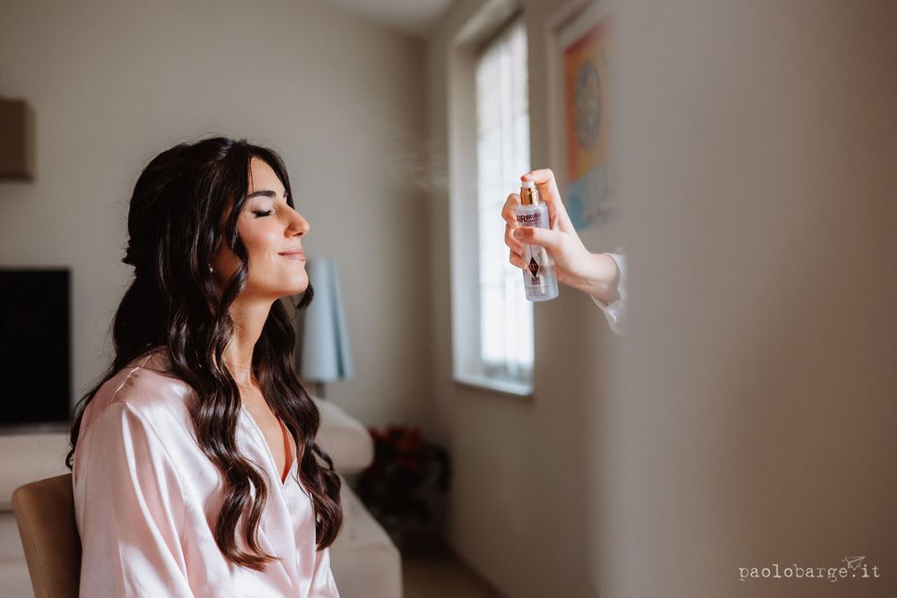 Wedding preparation moment with makeup artist using setting spray.