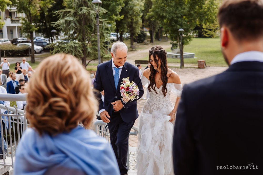 Outdoor wedding ceremony scene with guests watching procession.