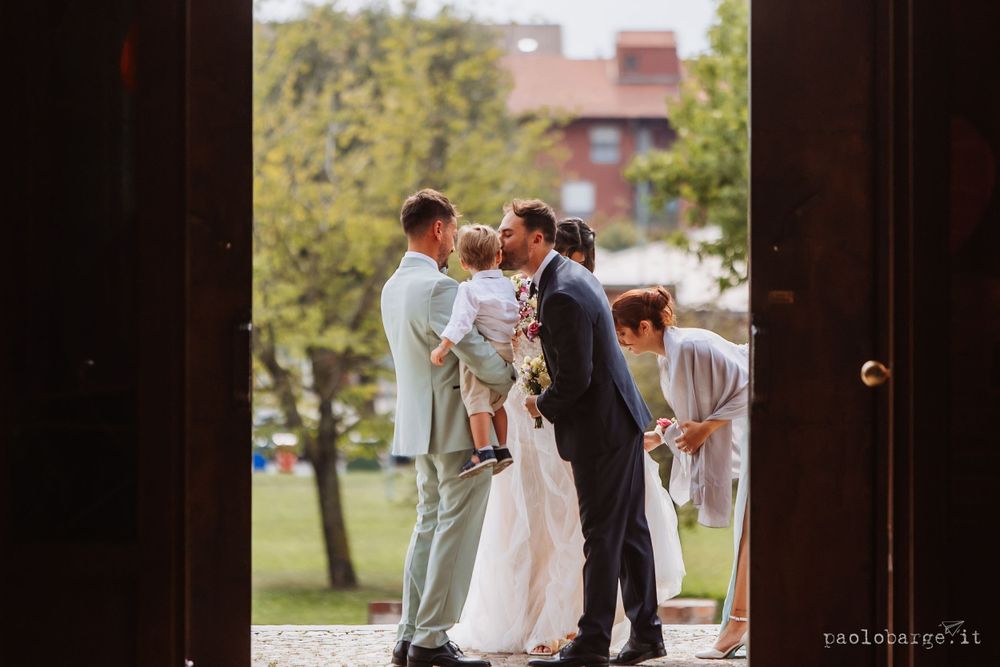 A wedding ceremony takes place outdoors with guests gathered around during a summer day.
