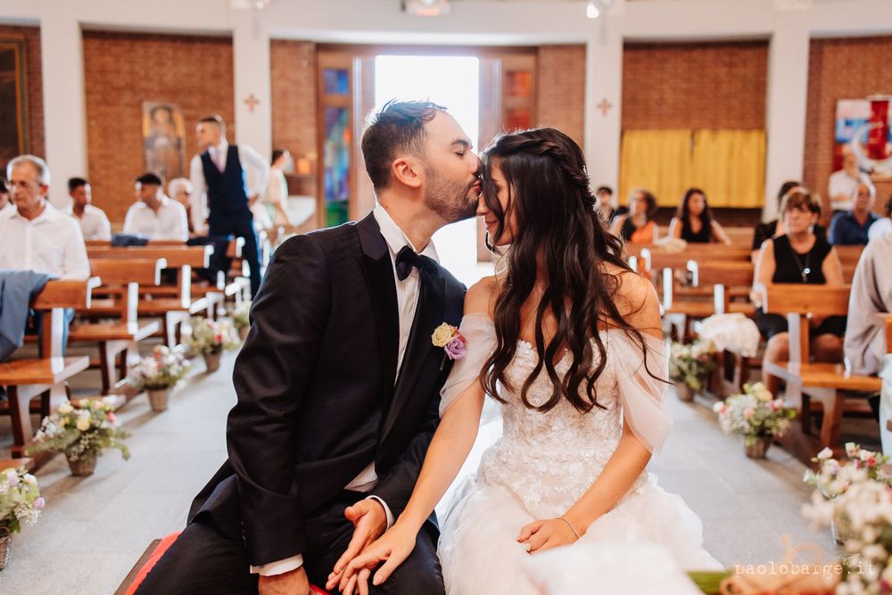 Intimate wedding ceremony moment in a church with floral aisle decorations.