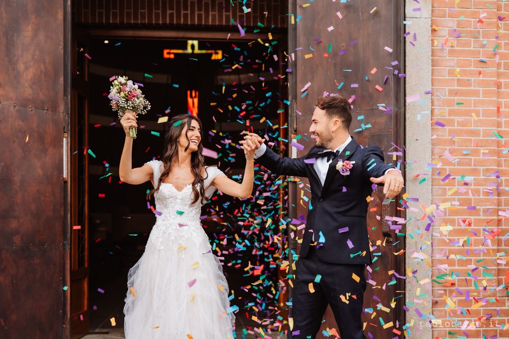 Newlyweds celebrate with colorful confetti as they exit their wedding ceremony.