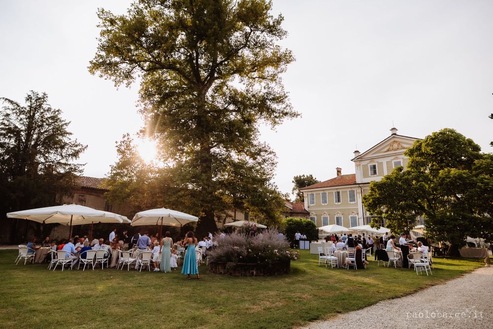 Outdoor wedding reception setup with white umbrellas and tables on an elegant estate lawn.