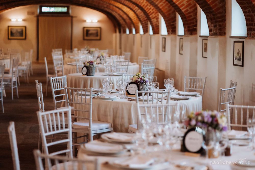 Elegant wedding reception venue with arched ceiling and white chiavari chairs set for dinner celebration.