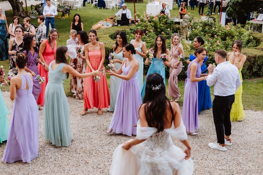 Wedding party celebrating outdoors with guests in colorful pastel dresses.