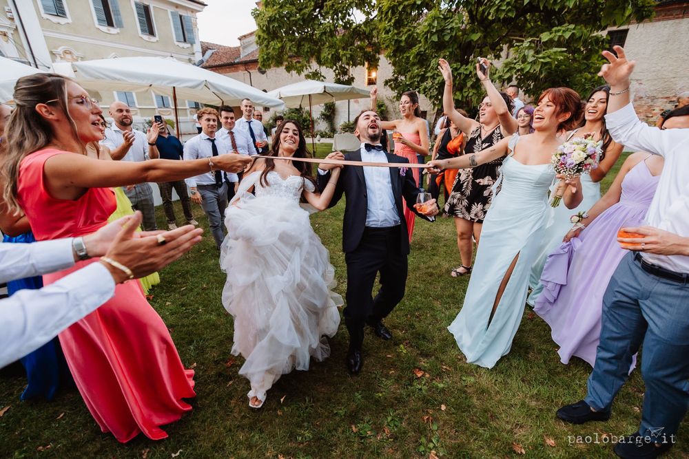 Wedding party dancing together in a garden setting with joyful celebration and movement.