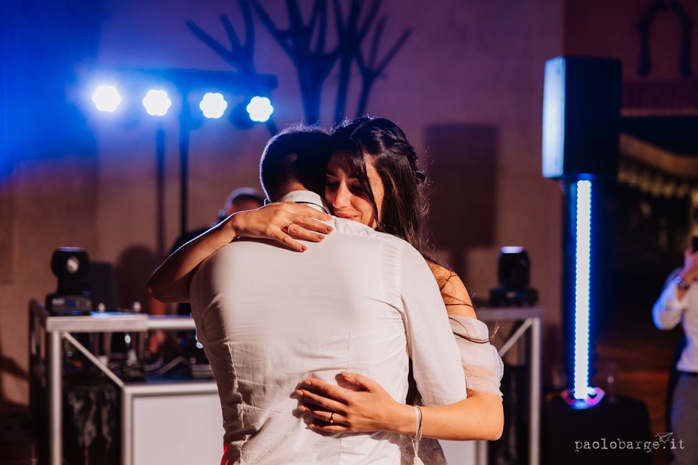 Intimate dance moment captured under blue stage lighting at wedding reception.